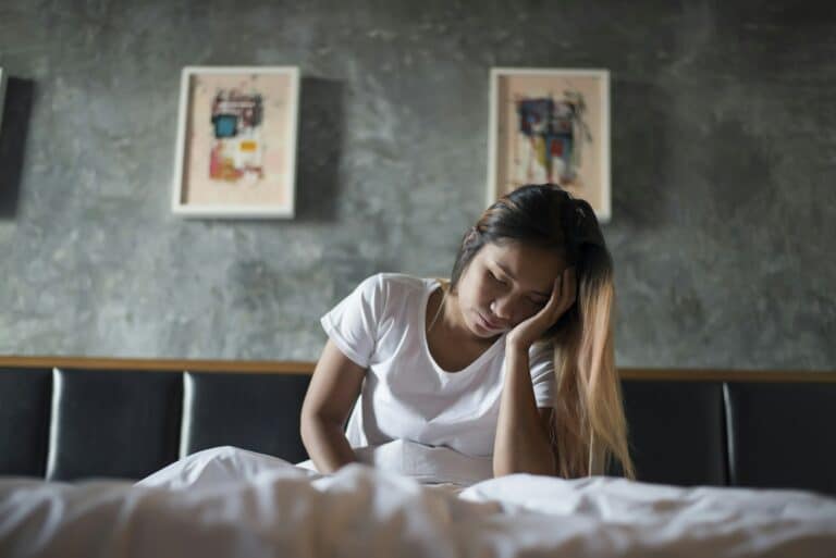 Depressed woman with headache hand holding her head on the bed